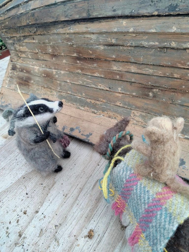 several felted creatures inspect an old model boat of some size